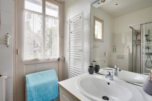 een witte badkamer met een wastafel en een spiegel bij Maison familale au panorama de reve in Saint-Cast-le-Guildo
