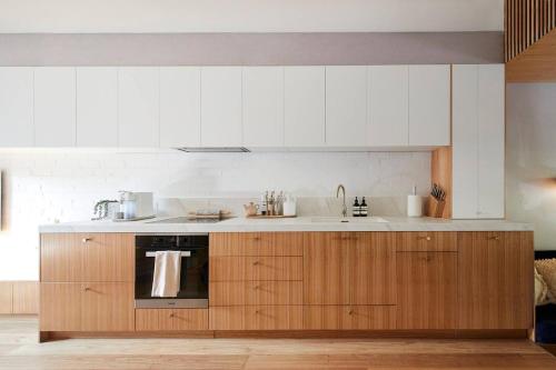 a kitchen with wooden cabinets and a sink at Canopy Terrace - Retreat to Voguish Urban Charm in Melbourne