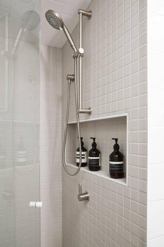 a shower with two black bottles on a shelf in a bathroom at Canopy Terrace - Retreat to Voguish Urban Charm in Melbourne