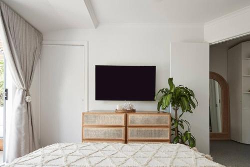a bedroom with a tv on a white wall at Canopy Terrace - Retreat to Voguish Urban Charm in Melbourne