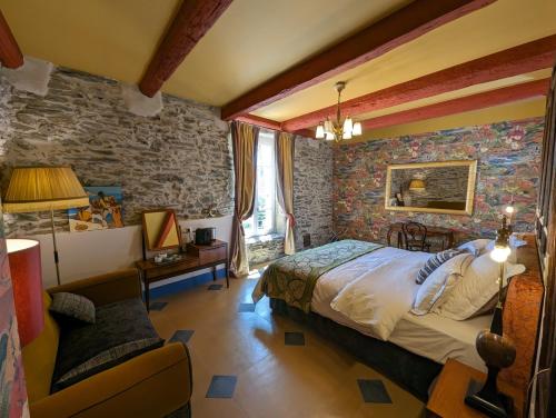 ein Schlafzimmer mit einem Bett und einer Steinmauer in der Unterkunft LA GALANTE in Faugères