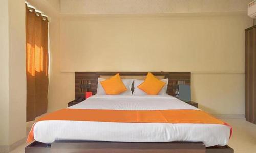 FabHotel Gargi Suites Shivajinagar في بيون: غرفة نوم بسرير كبير ومخدات برتقالية وبيضاء