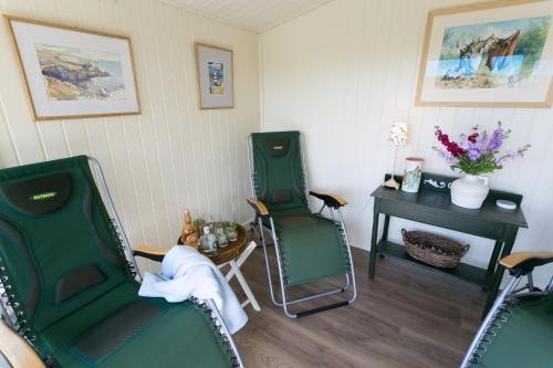 two green chairs and a table in a room at Pentir in Penmon