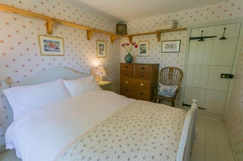 a bedroom with a white bed and a chair at Pentir in Penmon