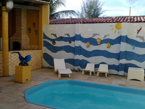 a swimming pool with chairs and a fence with a mural at Apartamento Mobiliado AptCE in Fortaleza