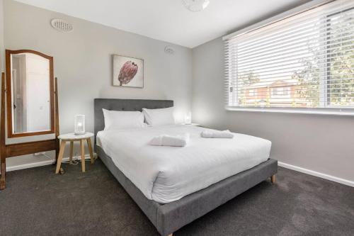 une chambre avec un grand lit blanc et une fenêtre dans l'établissement Rosewood Lodge - Cottage Charm off High Street, à Melbourne