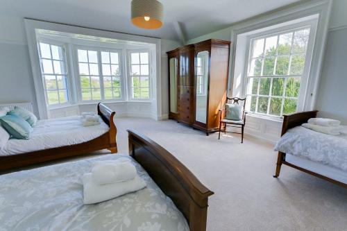 a bedroom with two beds and two windows at Plas Cichle in Beaumaris