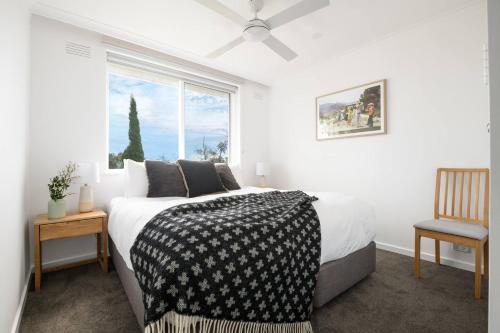 a bedroom with a bed and a window and a chair at The Lookout - Sunny St Kilda Contemporary in Melbourne