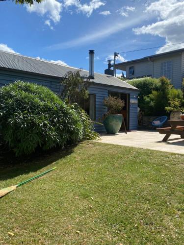 a house with a yard with a bench and a building at Beach Buoy Opossum Bay in South Arm