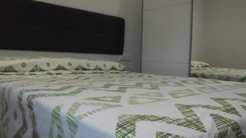 ein Bett mit einer grünen und weißen Decke drauf in der Unterkunft Apartamentos Atlas Terrassa I in Terrassa