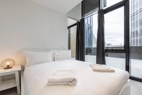 a bedroom with a white bed with a large window at Sky-High City Luxury with Huge Deck and Shared Pool in Melbourne