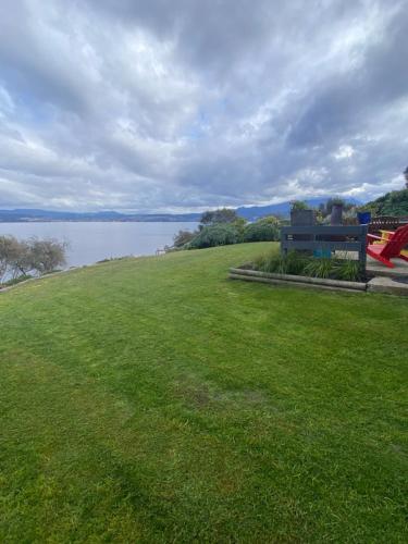 a park bench sitting on the grass near a lake at Beach Buoy Opossum Bay in South Arm