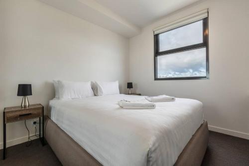 - une chambre blanche avec un grand lit et une fenêtre dans l'établissement Light-filled Stylish Living in Diverse Hawthorn, à Melbourne