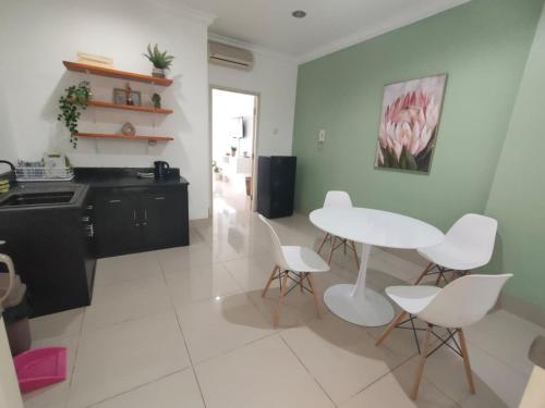 eine Küche mit einem weißen Tisch und weißen Stühlen in der Unterkunft Apartemen MTC Unit 626 in Manado