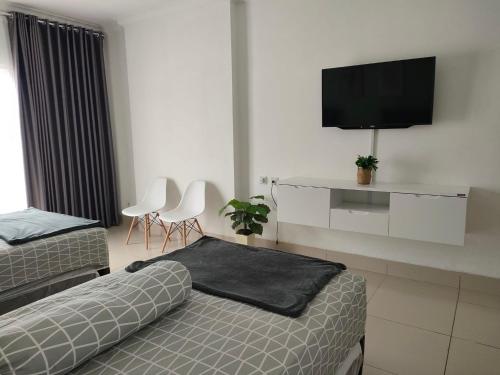 a hotel room with two beds and a flat screen tv at Apartemen MTC Unit 626 in Manado