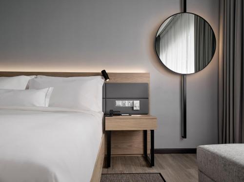 AC Hotel by Marriott Kuala Lumpur في كوالالمبور: غرفة نوم مع سرير ومرآة على الحائط
