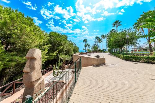 een loopbrug met een hek en palmbomen en de oceaan bij El Coloso Loft 1 in Benalmádena
