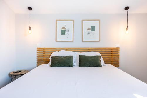 een slaapkamer met een wit bed en 2 groene kussens bij Angra Charming Suites by Seewest in Angra do Heroísmo