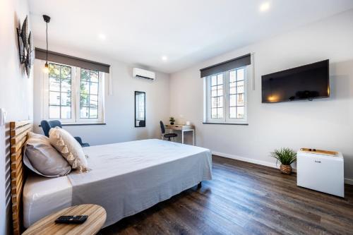 a bedroom with a bed and a flat screen tv at Angra Charming Suites by Seewest in Angra do Heroísmo