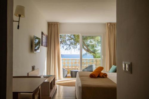 a hotel room with a bed and a large window at Apartamentos Es Caló in Es Calo