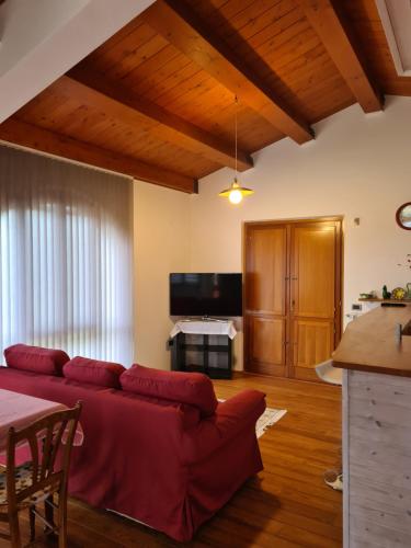 uma sala de estar com um sofá vermelho e uma televisão em Villa Scarialetto nel Parco Naturale di Monte Cucco em Sigillo