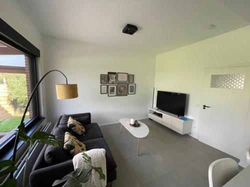 een woonkamer met een bank en een tv bij BierBee in Bierbeek