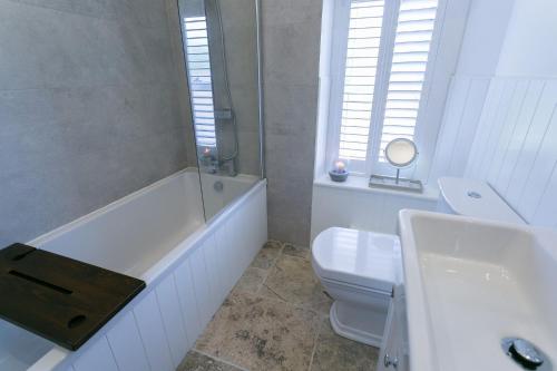 ein Badezimmer mit einer Badewanne, einem WC und einem Waschbecken in der Unterkunft Shell Cottage in Menai Bridge