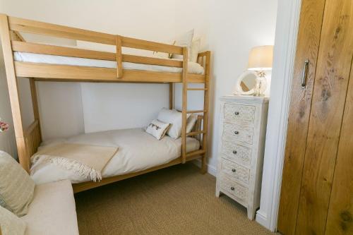 a bedroom with two bunk beds and a dresser at Shell Cottage in Menai Bridge