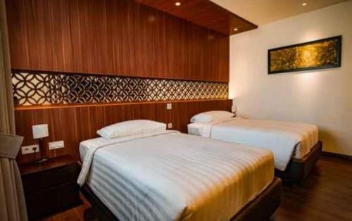 two beds in a hotel room with wooden walls at Villa Rancabango Hotel & Resort Garut in Tarogong