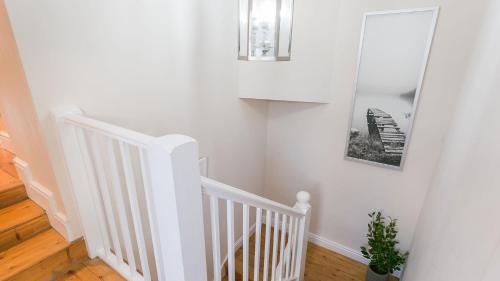 a white staircase with a mirror and a picture on the wall at The Hideaway Beaumaris in Beaumaris