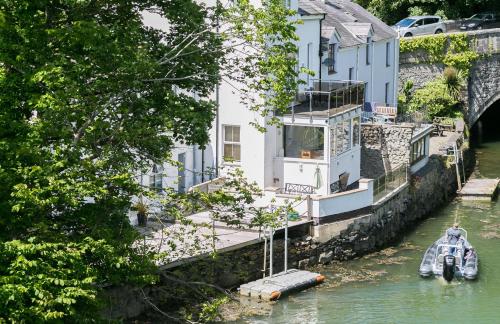 a house on the side of a river with a boat at The Moorings in Menai Bridge