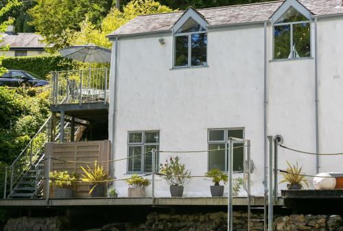 a white house with plants on a dock at The Moorings in Menai Bridge