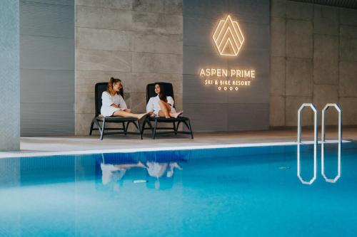 dos mujeres sentadas en sillas junto a una piscina en Aspen Prime Ski & Bike Resort - basen, sauna, jacuzzi, siłownia w cenie pobytu, en Głuchołazy