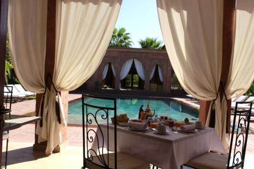a table and chairs in front of a swimming pool at Domaine Casa Cecilia in Marrakech