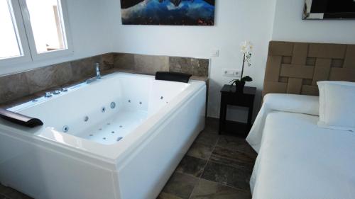 a white bath tub in a room with a bed at SUITE ORQUIDEA in Benalup Casas Viejas