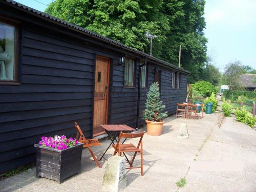 a black house with a table and chairs and a patio at Five Cottages in AONB and a Hobbit House! in Canterbury