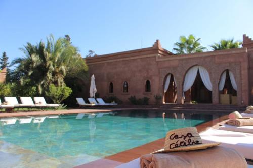 a swimming pool with chairs and a building at Domaine Casa Cecilia in Marrakech