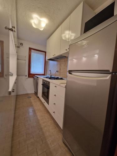a kitchen with a stainless steel refrigerator and white cabinets at L'Atelier du Temps - Sole e Luna in Cogne