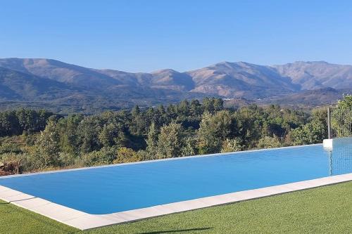 una gran piscina azul con montañas en el fondo en Casa rural Atalanta de la Vera, en Jaraíz de la Vera