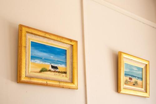 two paintings of a farm on a wall at De Rusty Farm in De Rust