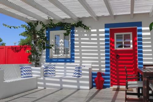 a house with a red door and a couch on a patio at Casa Alentejana com piscina e grande jardim 
