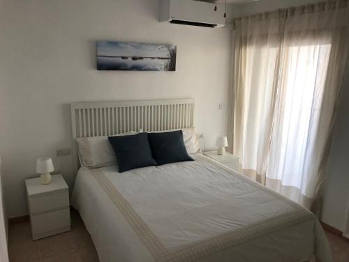 a bedroom with a white bed with blue pillows at Poseidón Apartamento frente a la playa in Fuengirola