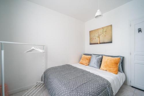 1 dormitorio con 1 cama con almohadas de color naranja y gris en L'Évasion Aulnaysienne - Appt pour 4, en Aulnay-sous-Bois