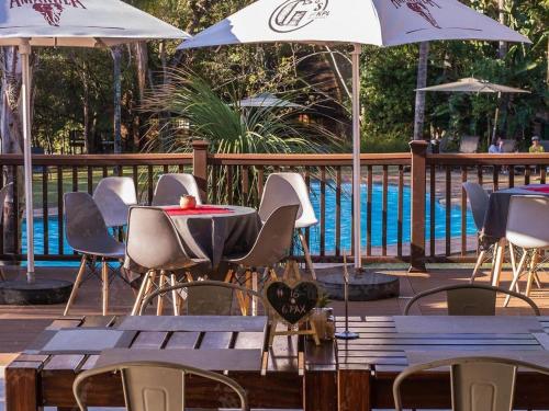 eine Gruppe von Tischen und Stühlen mit Sonnenschirmen neben einem Pool in der Unterkunft Kruger Park Lodge Unit 531 - PMP in Hazyview