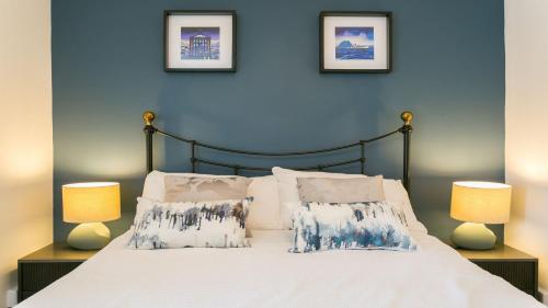 um quarto azul com uma cama com lençóis brancos e almofadas em Ty Melyn em Beaumaris