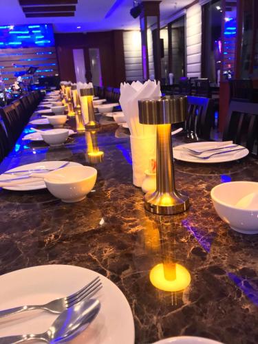 a long table with white plates and silver utensils at President Hotel Udonthani in Udon Thani