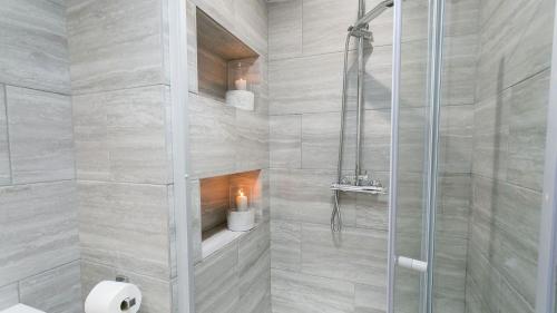 a bathroom with a shower with two candles in it at Anchor Cottage in Cemaes Bay