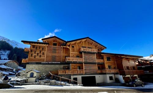 a large wooden building with snow on the ground at Hameau des Prodains - Résidence in Morzine