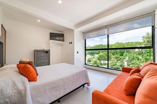 1 dormitorio con cama, sofá y ventana grande en 2099 - Casa Hera, en Santa Cruz Huatulco