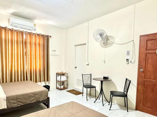 a bedroom with a bed and a table and chairs at PD Hostel in Ban Don Muang (1)